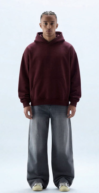 Person wearing a maroon hoodie and gray pants on a white background
